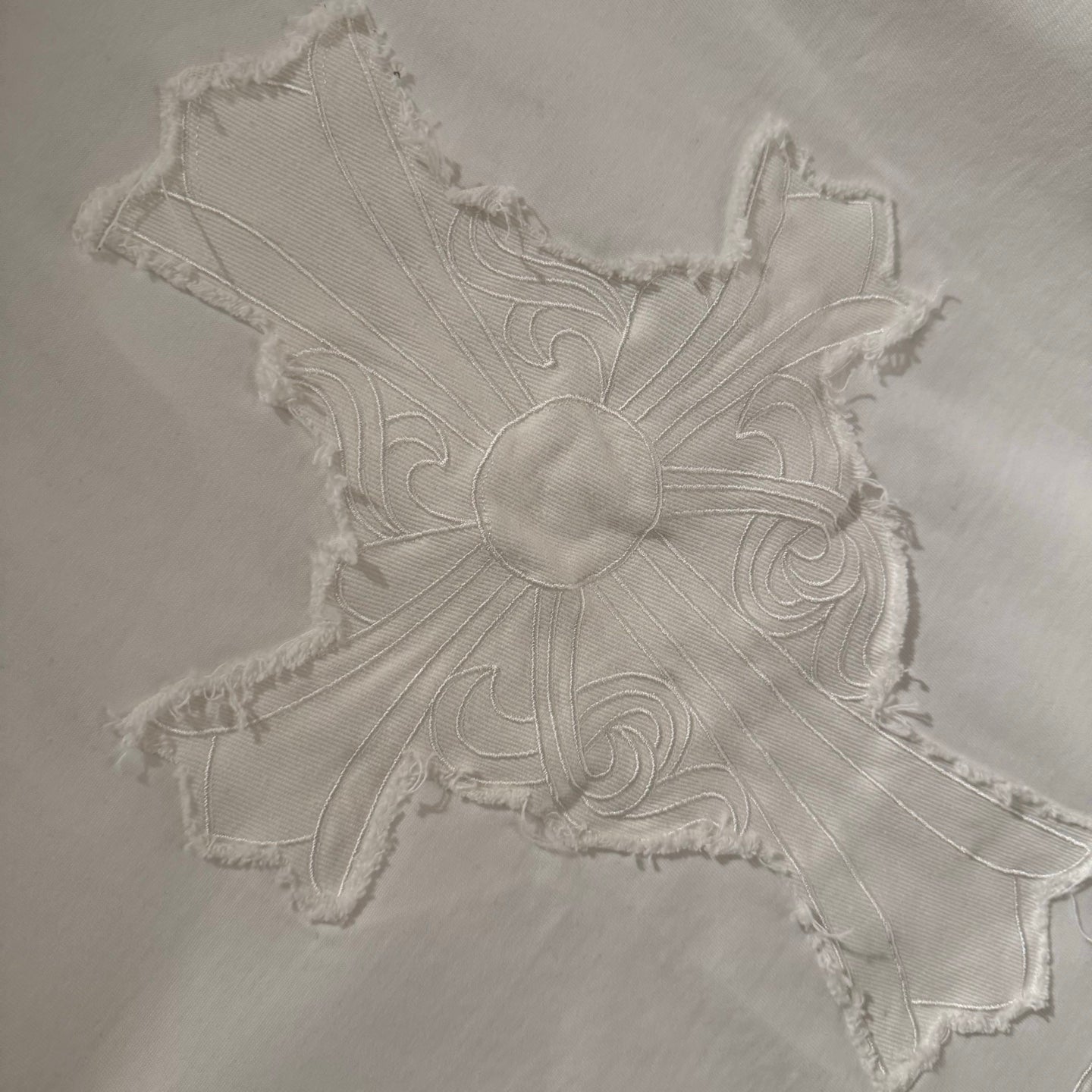 Embroidered cross applique on a white short-sleeve T-shirt