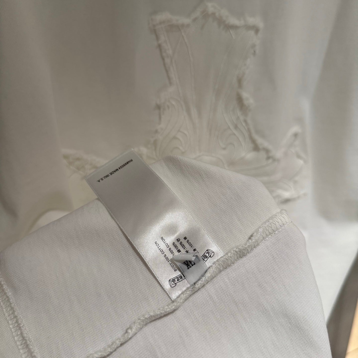 White short-sleeve T-shirt hem with care label and embroidered cross motif