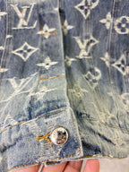 Louis Vuitton denim jacket sleeve and hem close-up with gold monogram print and metal button.