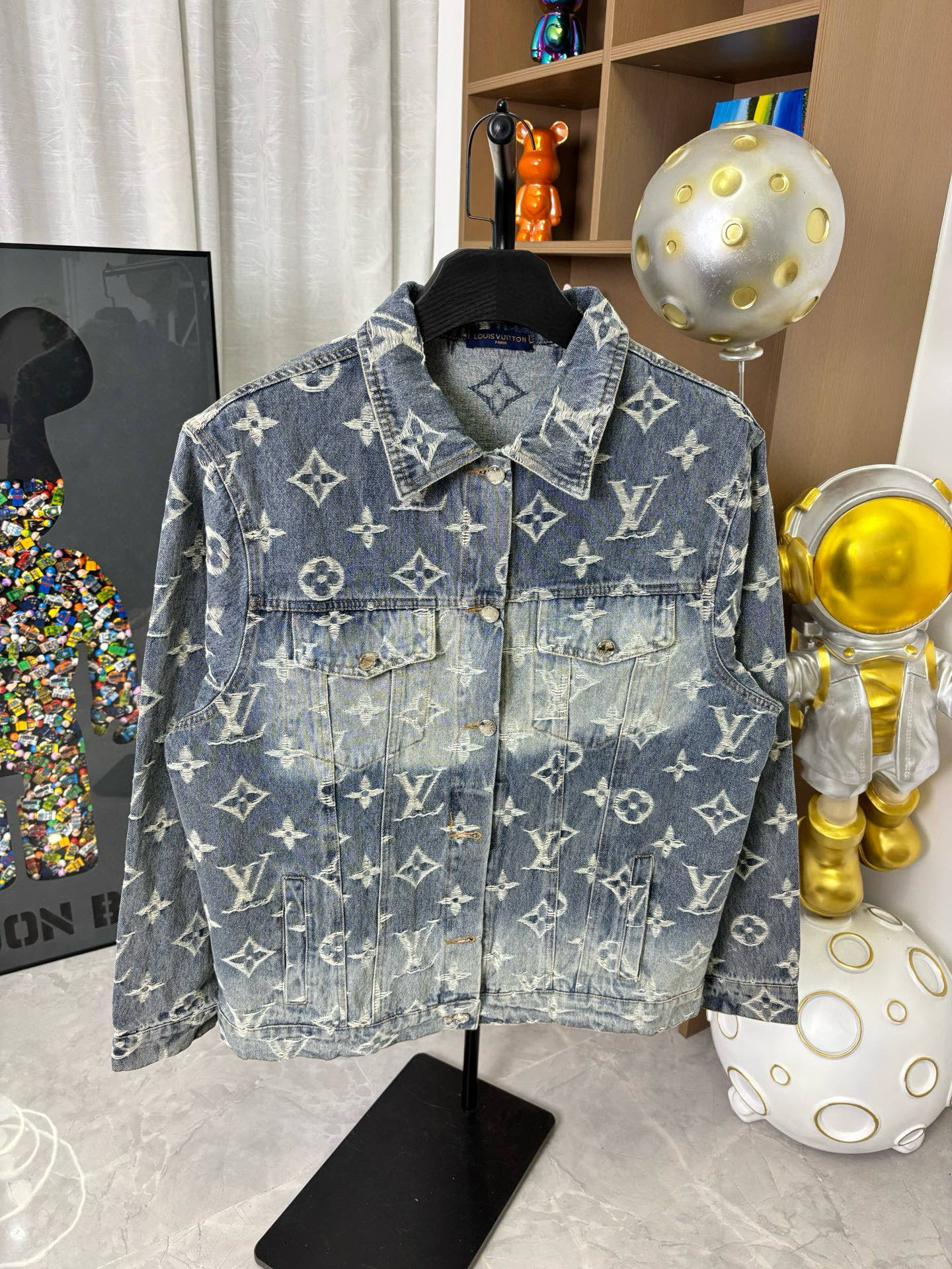 Louis Vuitton denim jacket front with blue wash, gold monogram print, flap chest pockets.