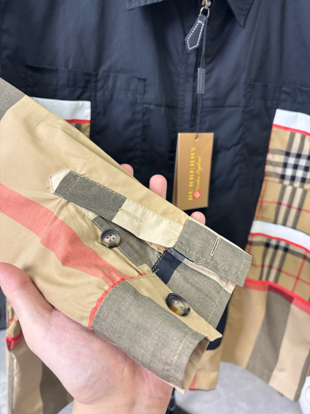 Burberry jacket sleeve close-up with buttons and navy placket over plaid