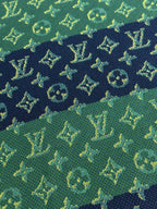 Close-up of textured knit fabric in green with navy and yellow monogram pattern