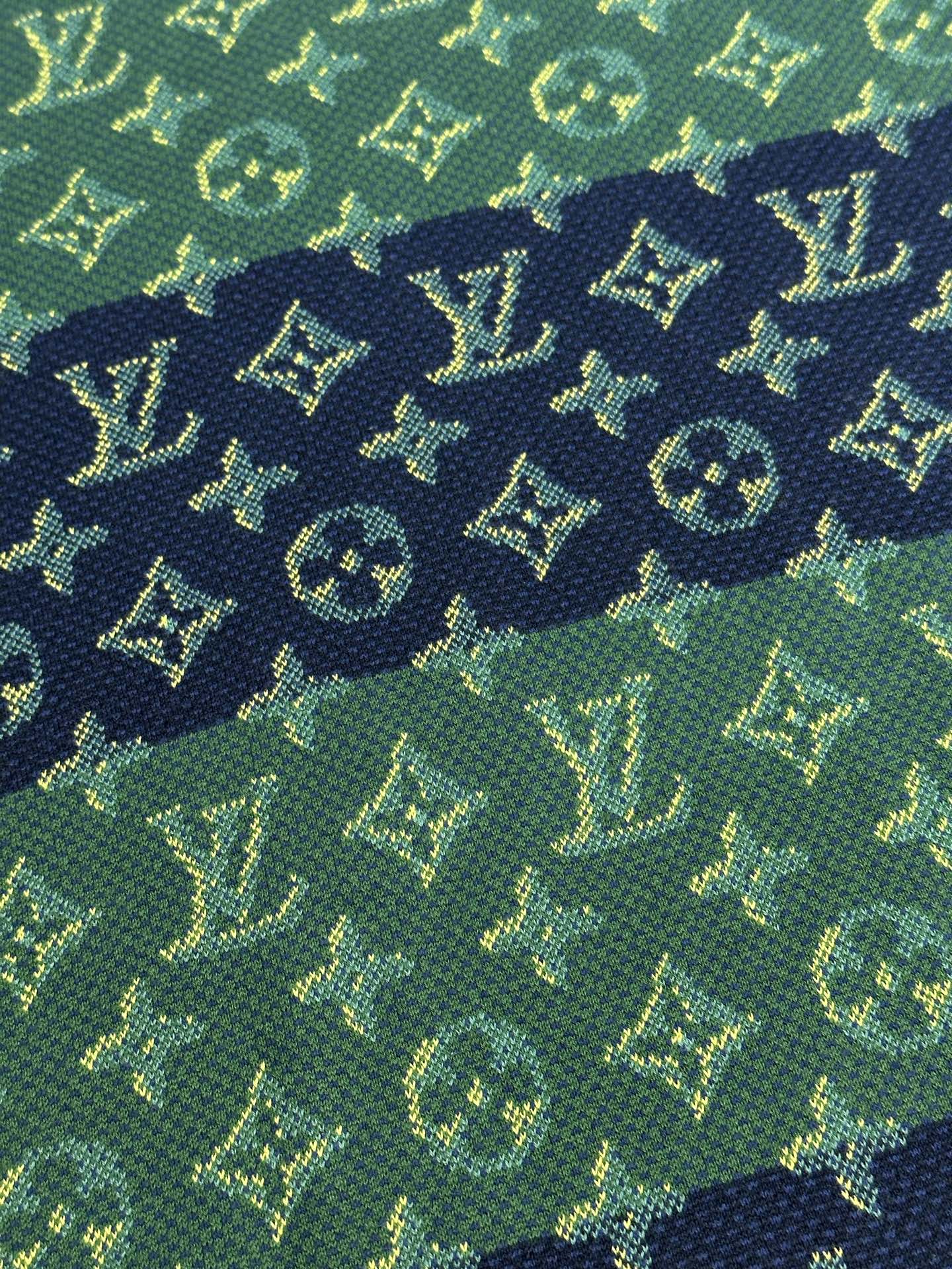 Close-up of textured knit fabric in green with navy and yellow monogram pattern