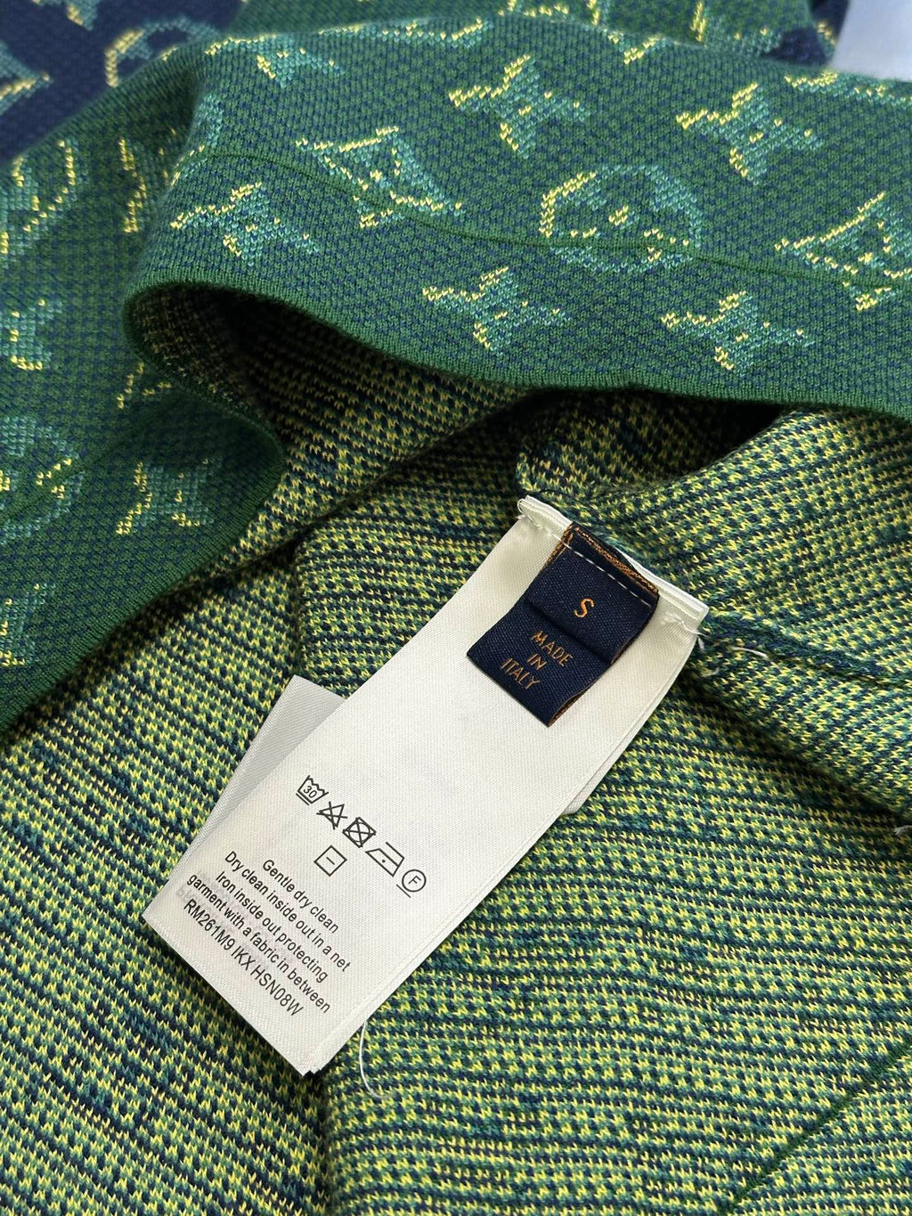 Woven interior neck tag and care label on green knit fabric