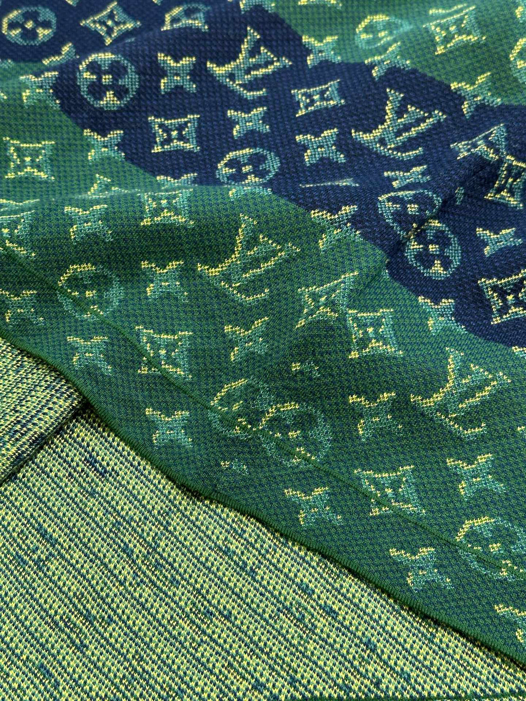 Close-up knit fabric with green and navy monogram motifs and yellow highlights
