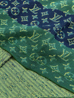 Close-up knit fabric with green and navy monogram motifs and yellow highlights