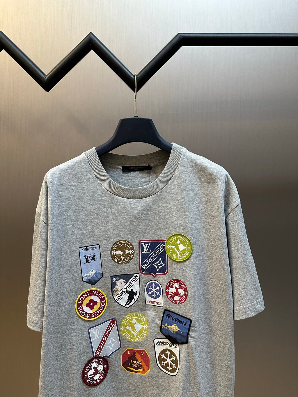 Grey T-shirt with centered multi-logo patch graphic and crew neckline