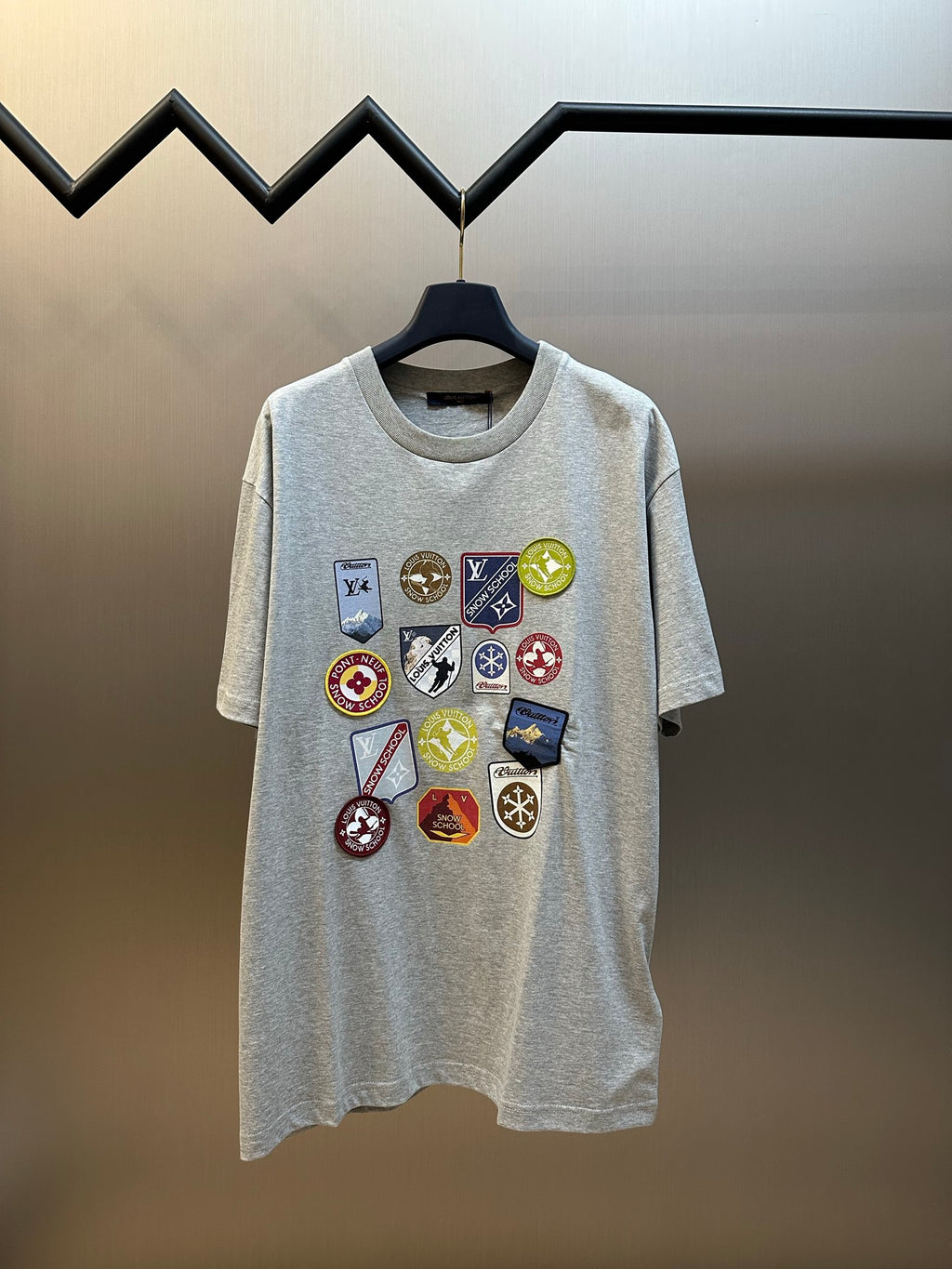 Grey T-shirt with multi-color logo patch graphic on the front