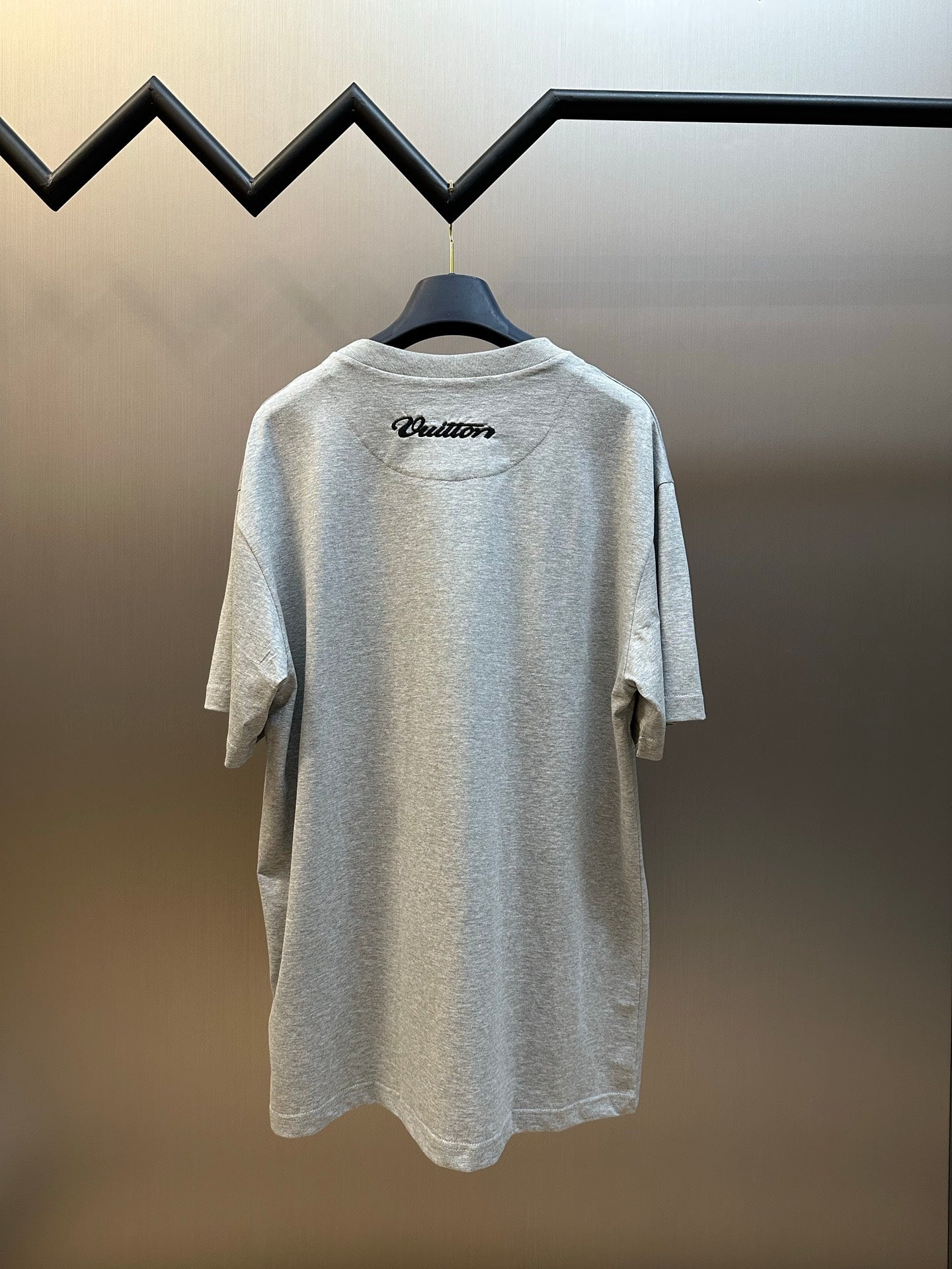 Grey T-shirt with small back logo text near the upper back