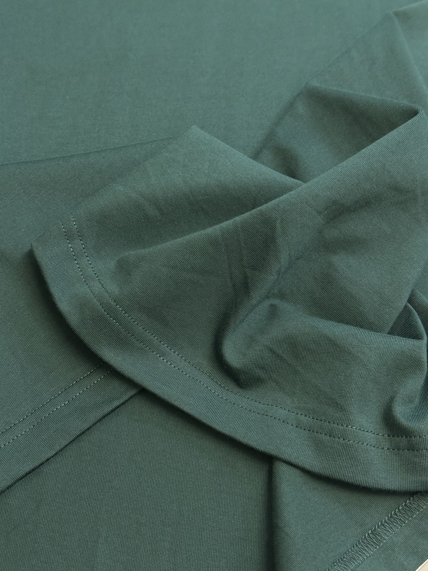 Green T-shirt fabric with visible seam and shoulder fold