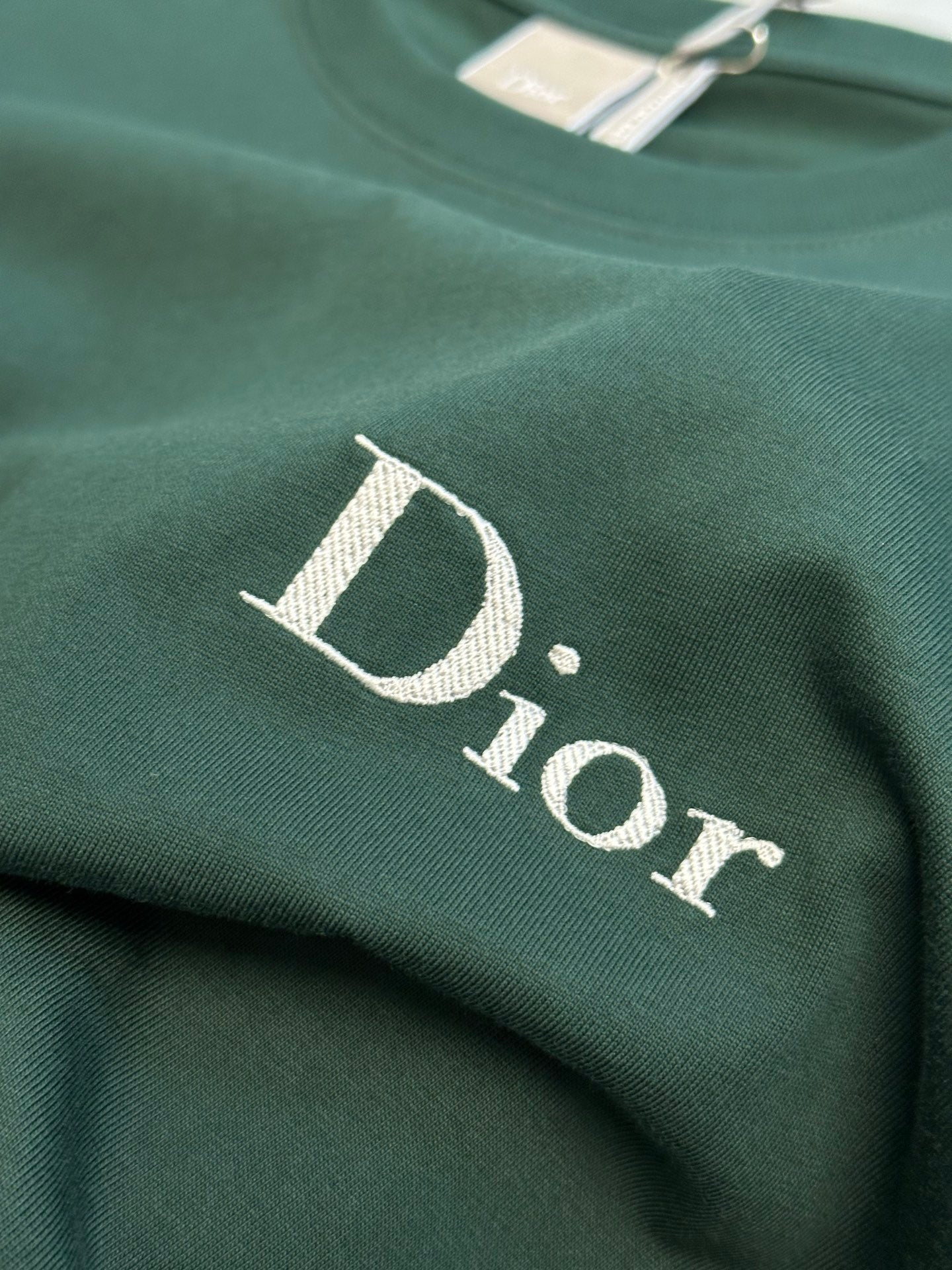 White Dior logo on dark green Dior short-sleeve T-shirt close-up