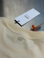 Cream T-shirt crew neck close-up with tags and stitched AMIRI logo