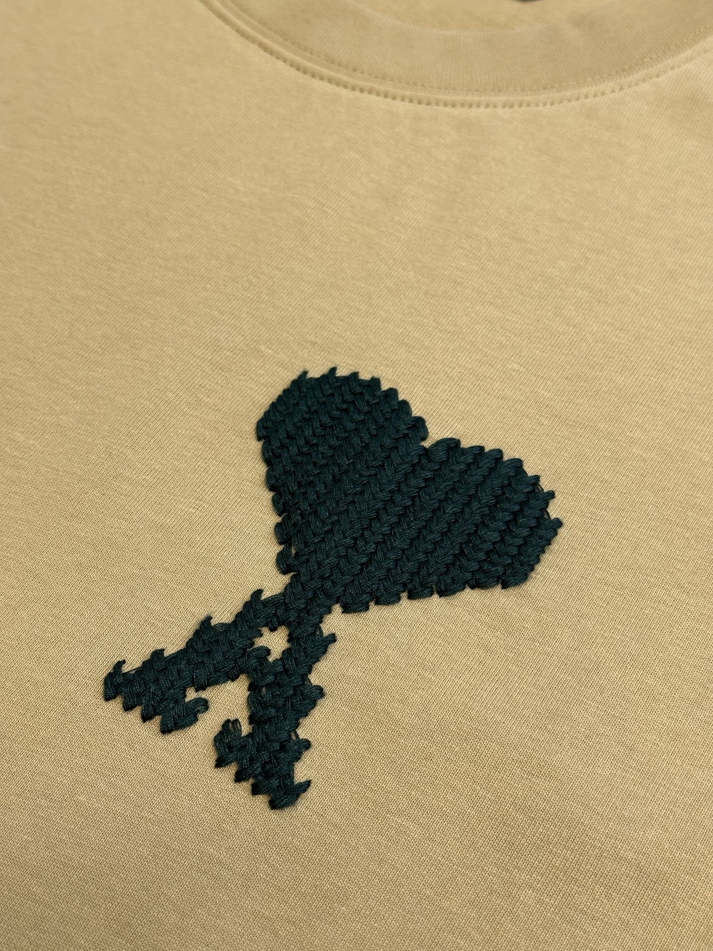 Beige T-shirt with textured black graphic print on the chest