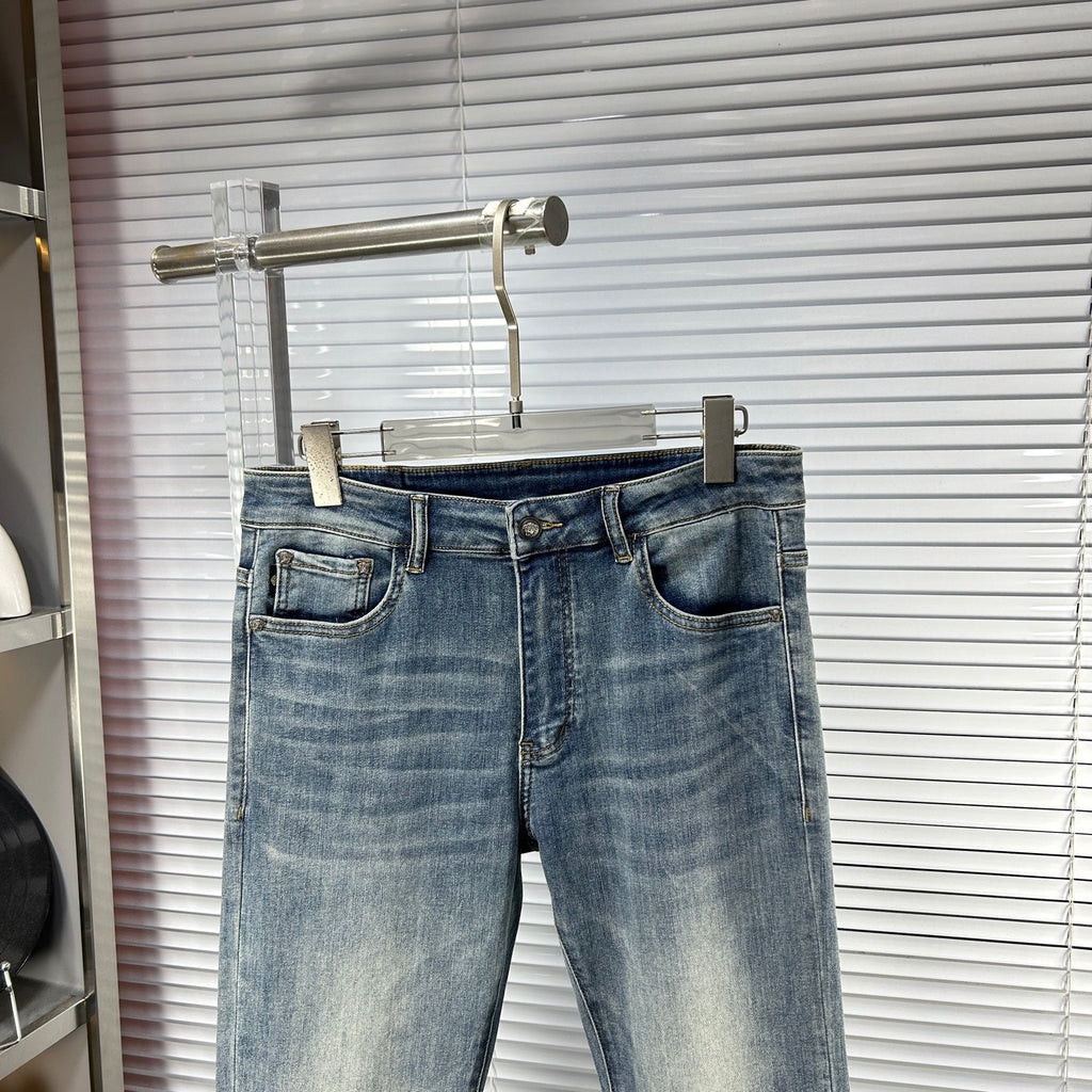 Blue denim jeans with waistband logo patch, front fly, and cuffed hem
