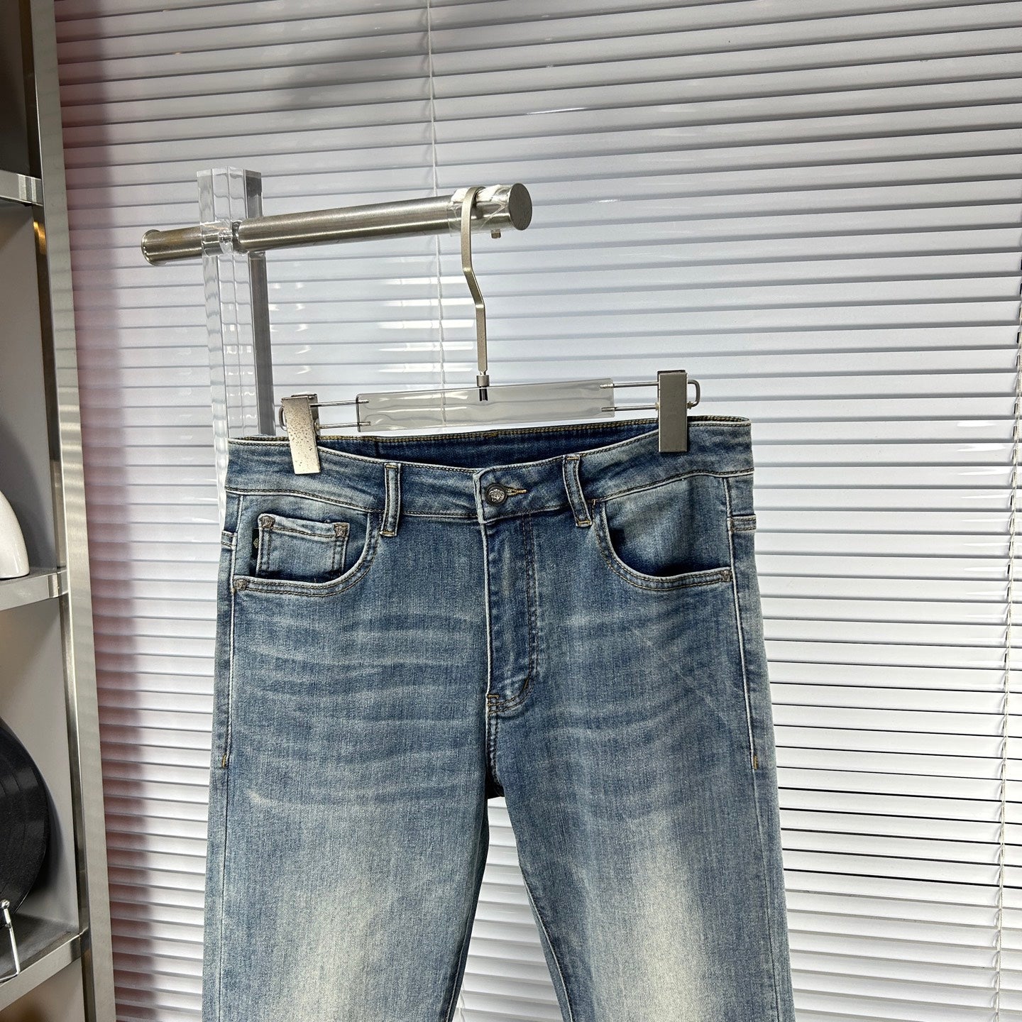 Blue denim jeans with waistband logo patch, front fly, and cuffed hem