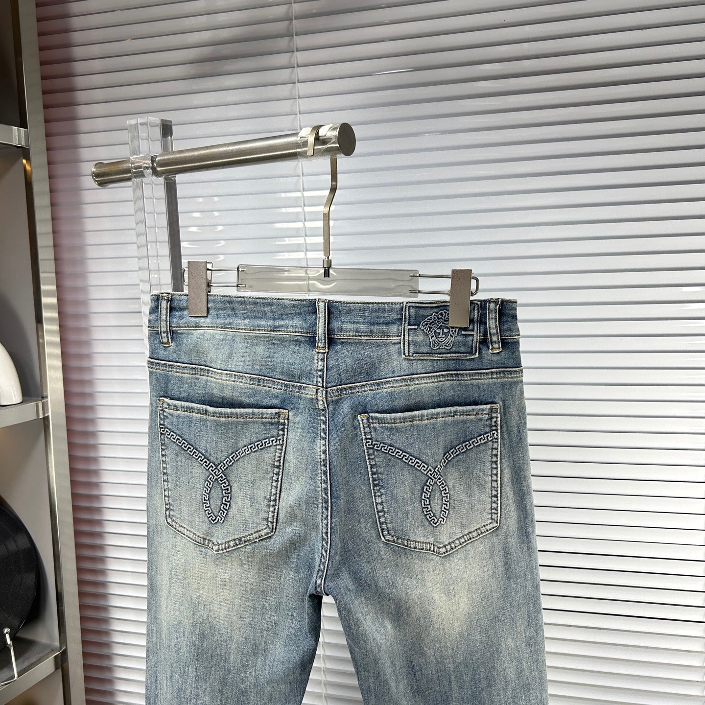 Light blue denim jeans with two front pockets and logo patch on waistband