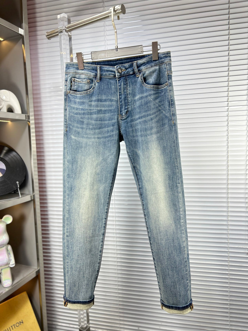 Light blue washed denim jeans on a hanger with straight-leg fit and belt loops