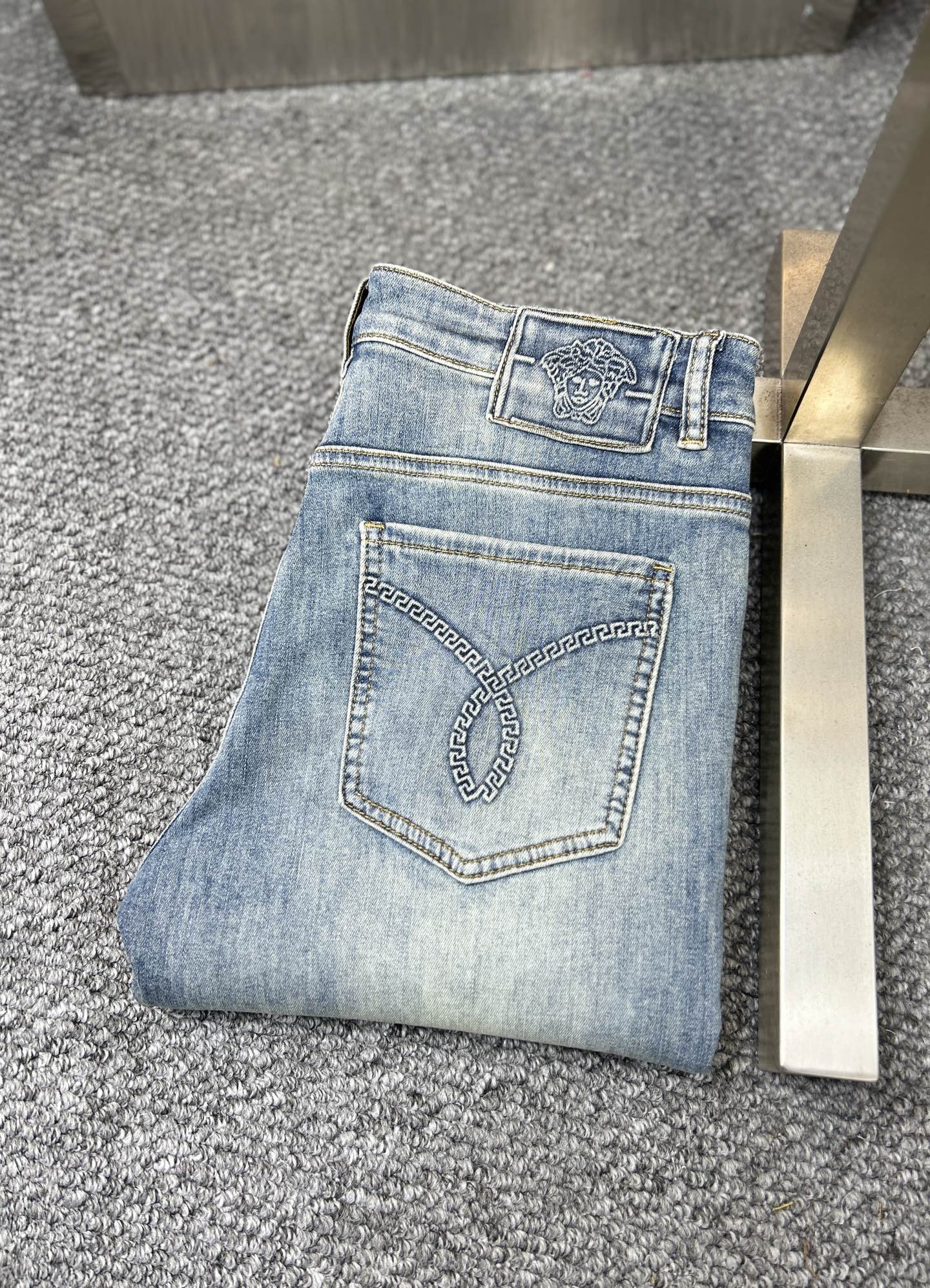 Light blue denim jeans with stitched pocket detail and metal button at waistband
