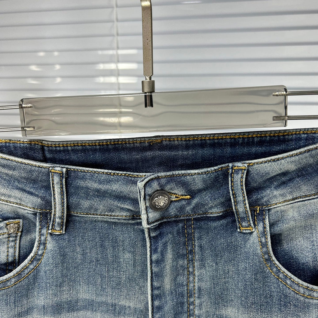 Denim jeans waistband with metal button and stitched logo patch at center