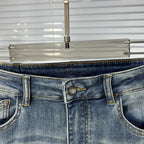 Denim jeans waistband with metal button and stitched logo patch at center