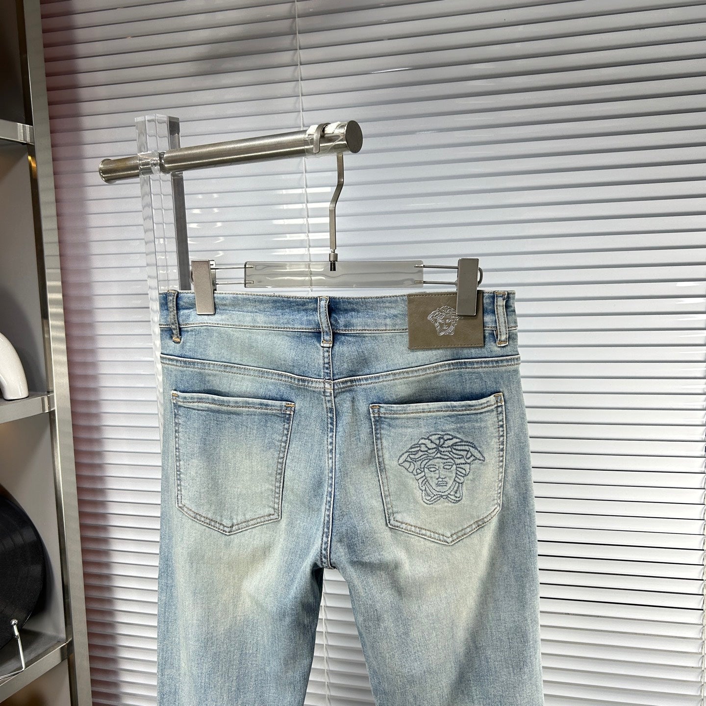 Light blue Versace jeans on hanger with front pockets and logo patch panel
