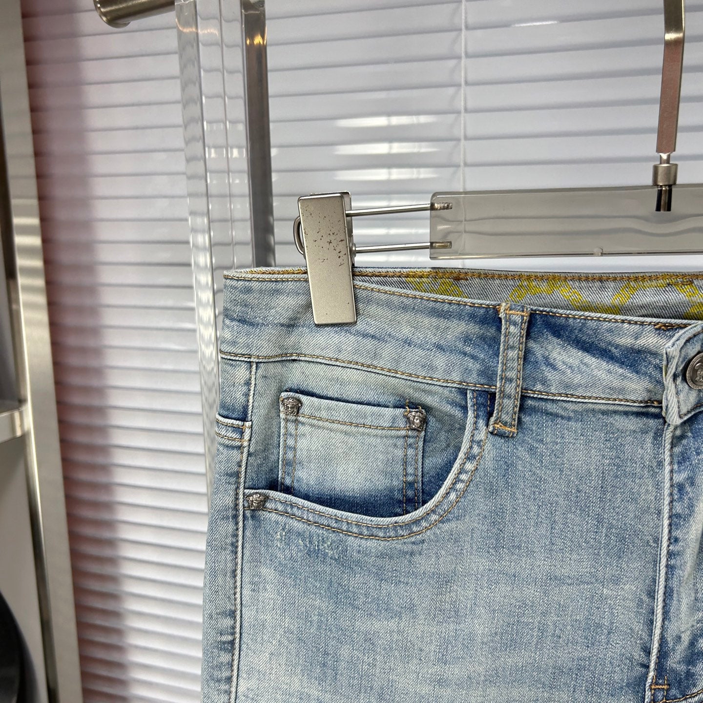Light blue denim jeans with front coin pocket and stitched waistband label area