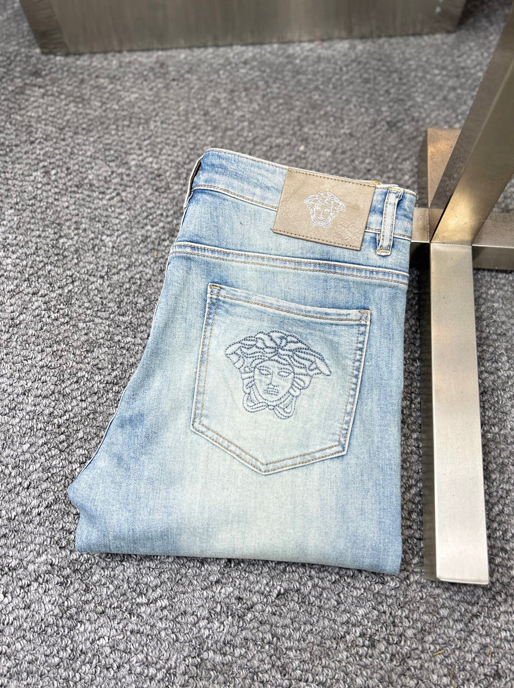 Light blue jeans with topstitched front pockets and Versace logo patch