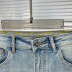 Light blue denim waistband with metal button, fly zipper, and belt loops