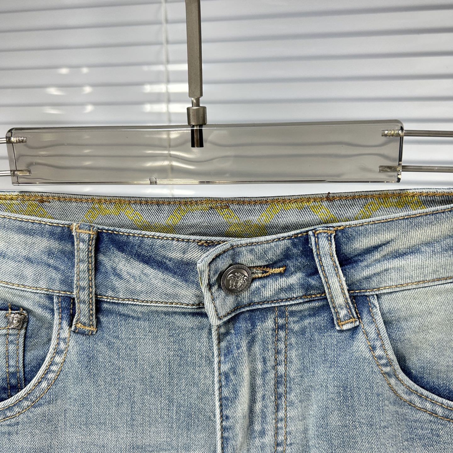 Light blue denim waistband with metal button, fly zipper, and belt loops
