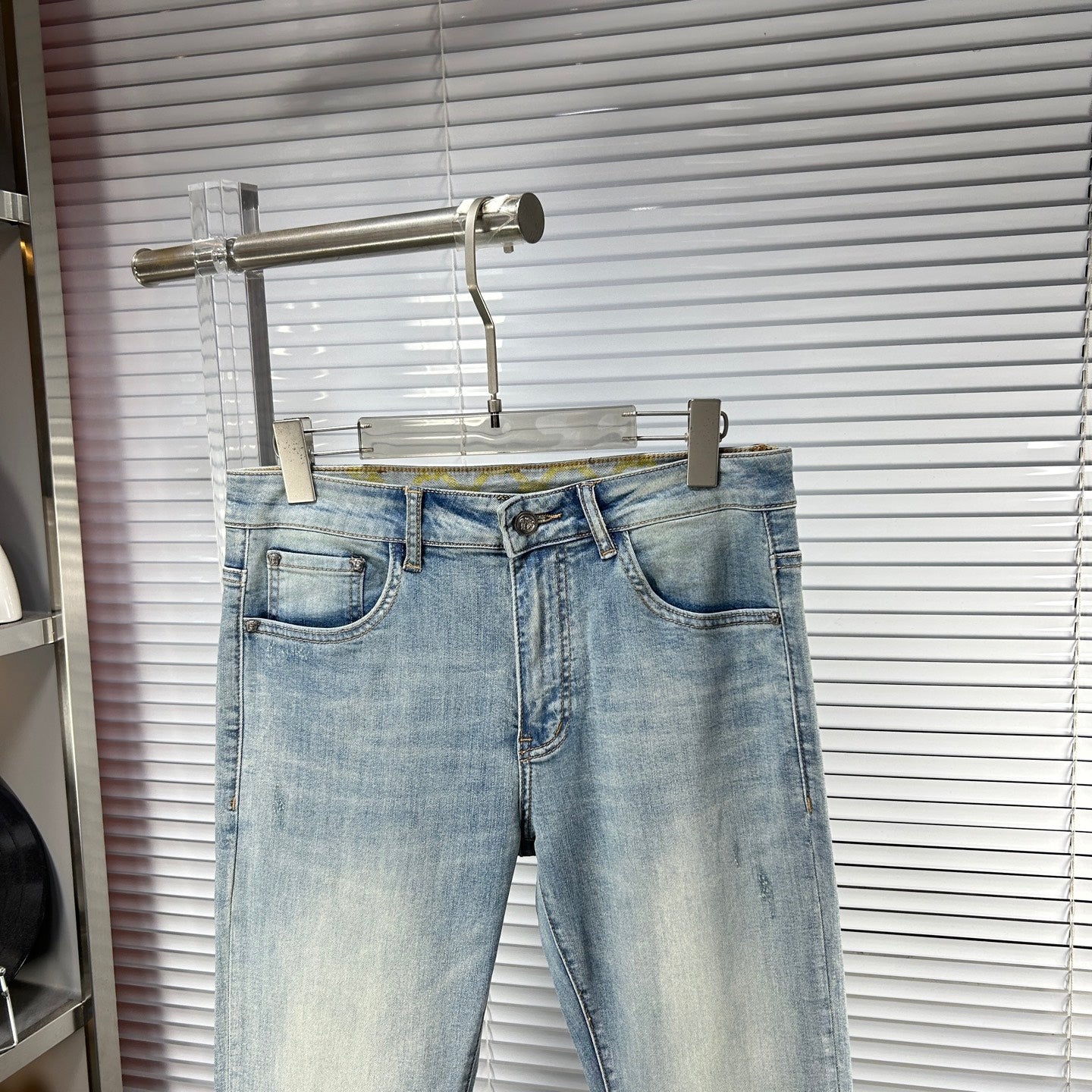 Light blue denim jeans with button fly, belt loops, and stitched front pockets
