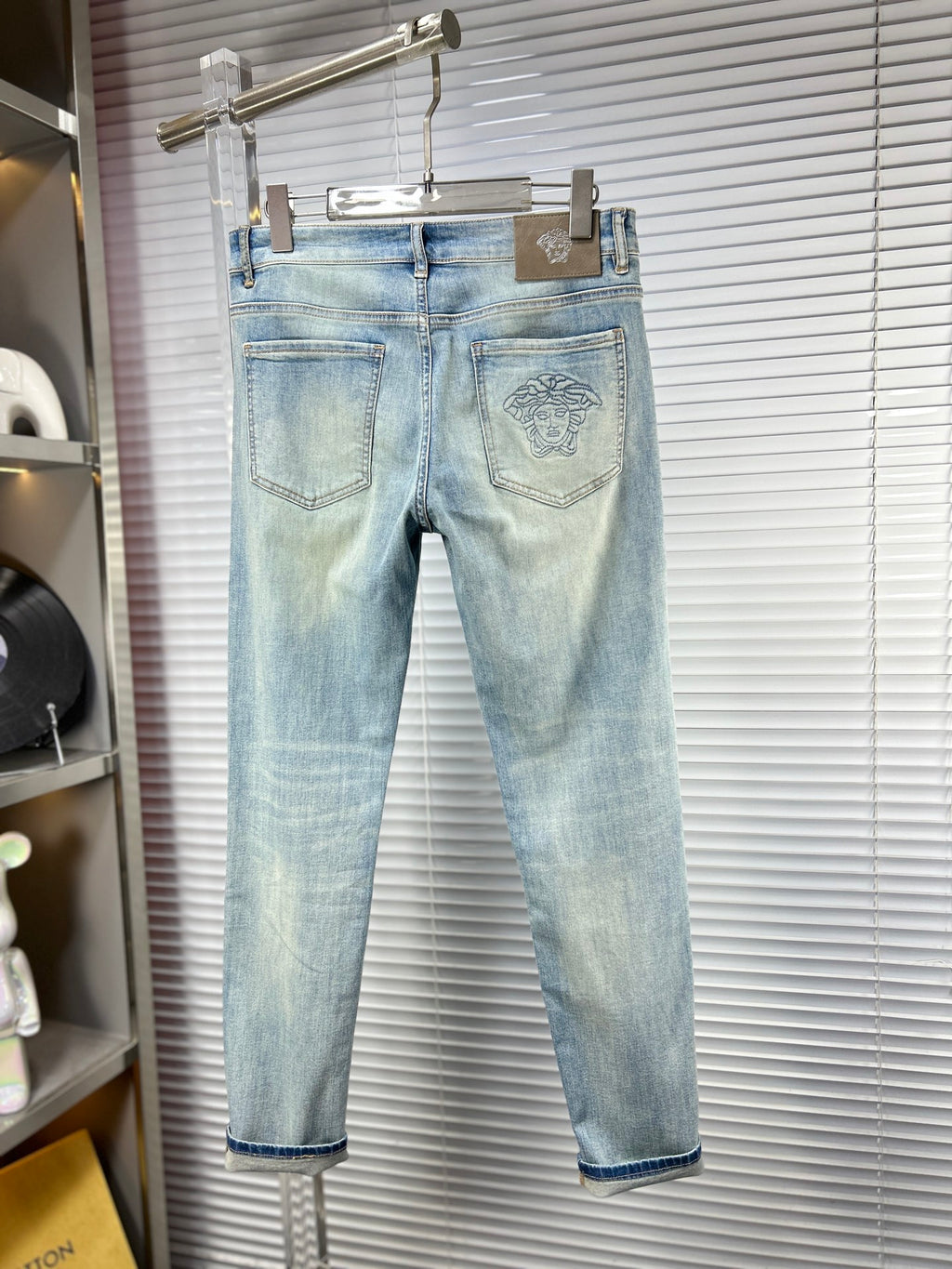 Light blue jeans with front pockets and faded Versace logo patch