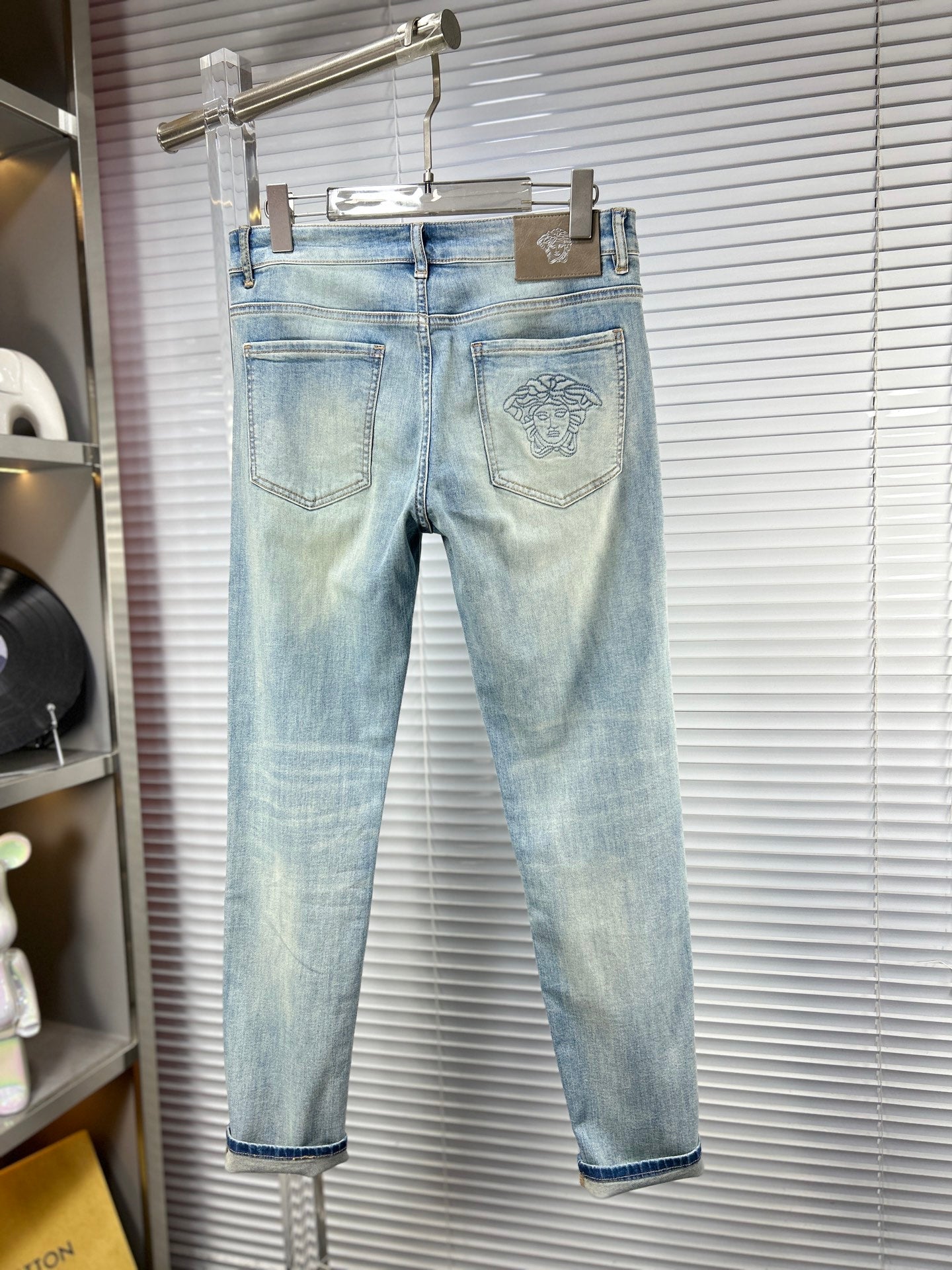 Light blue jeans with front pockets and faded Versace logo patch