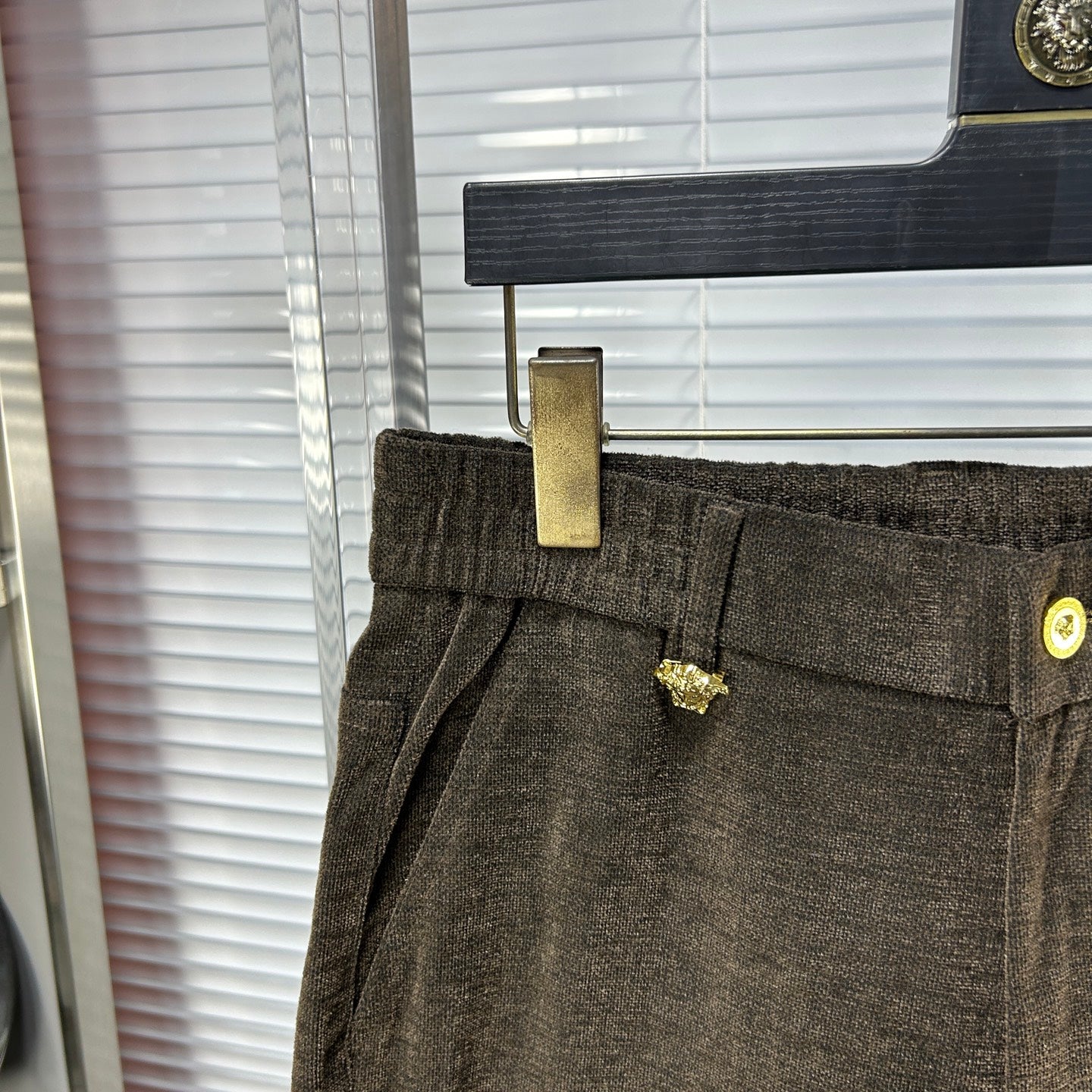 Versace trousers front close-up with side pocket, gold button detail, and belt loops