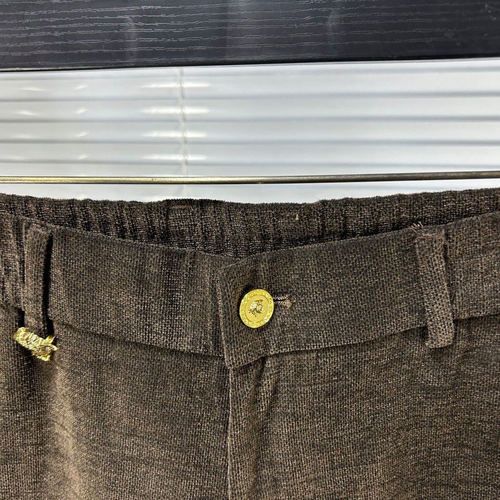 Versace trousers waistband close-up with gold logo button and textured fabric