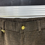 Versace trousers waistband close-up with gold logo button and textured fabric