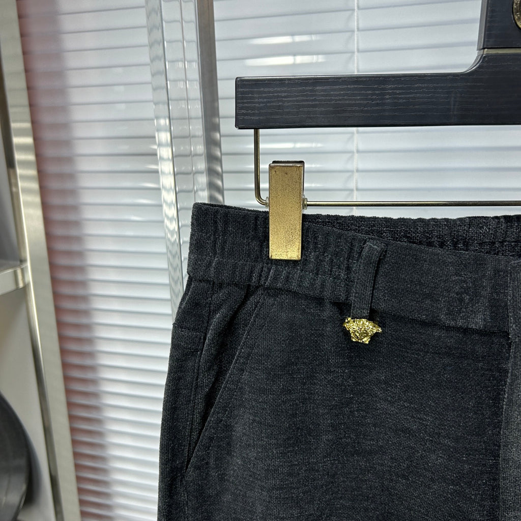 Dark trousers waist detail with gold-tone metal tag at belt loop