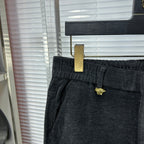 Dark denim pants close-up: buttoned waistband and gold-tone detail on belt loop