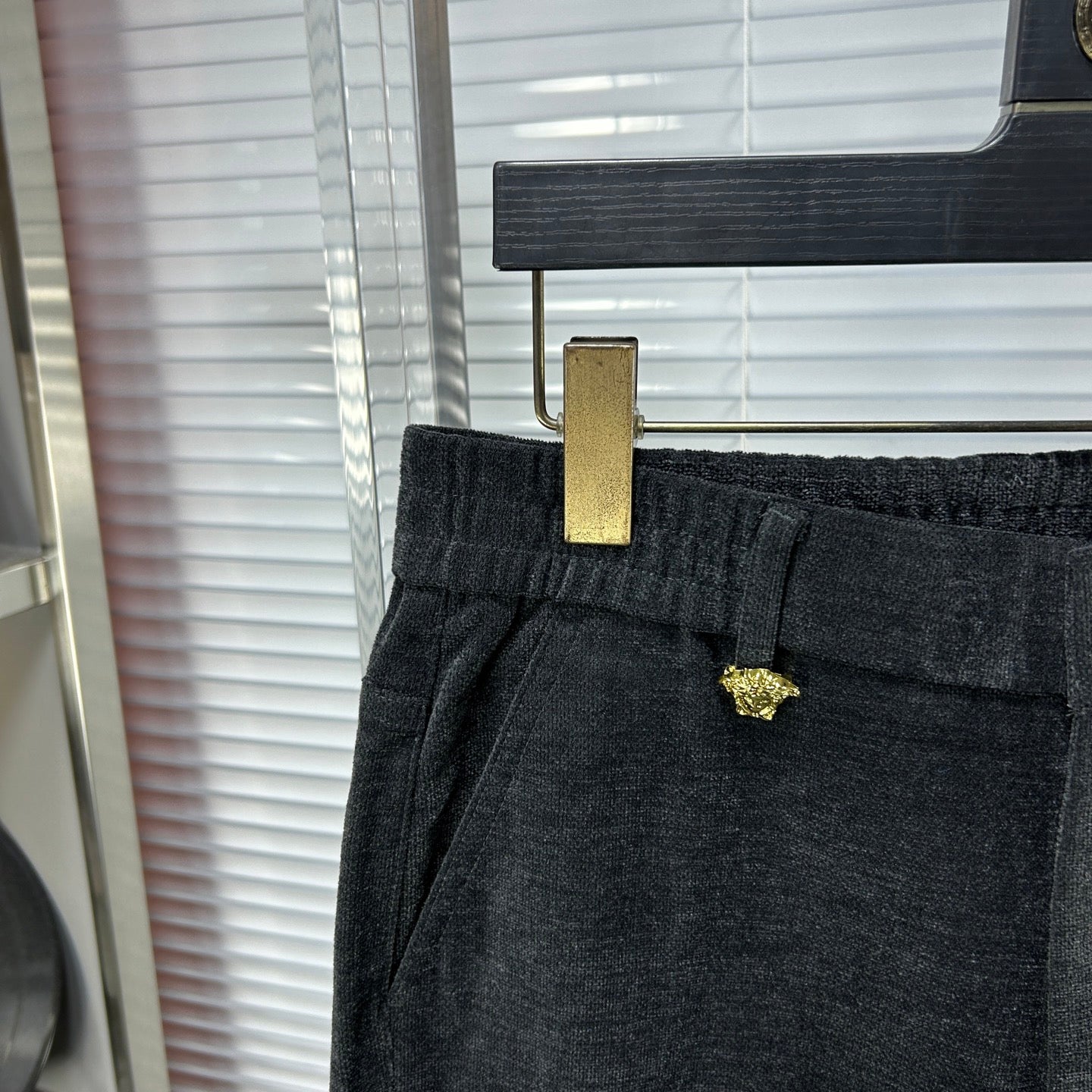 Dark denim pants close-up: buttoned waistband and gold-tone detail on belt loop