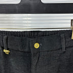 Dark denim waistband close-up with gold button and fabric texture