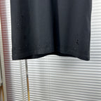 Black crew-neck T-shirt hem with scattered speckle and distressed dots