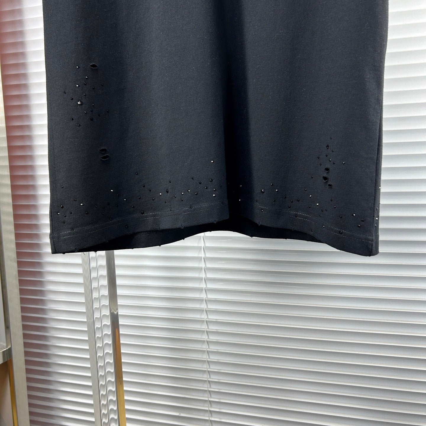 Black crew-neck T-shirt hem with scattered speckle and distressed dots