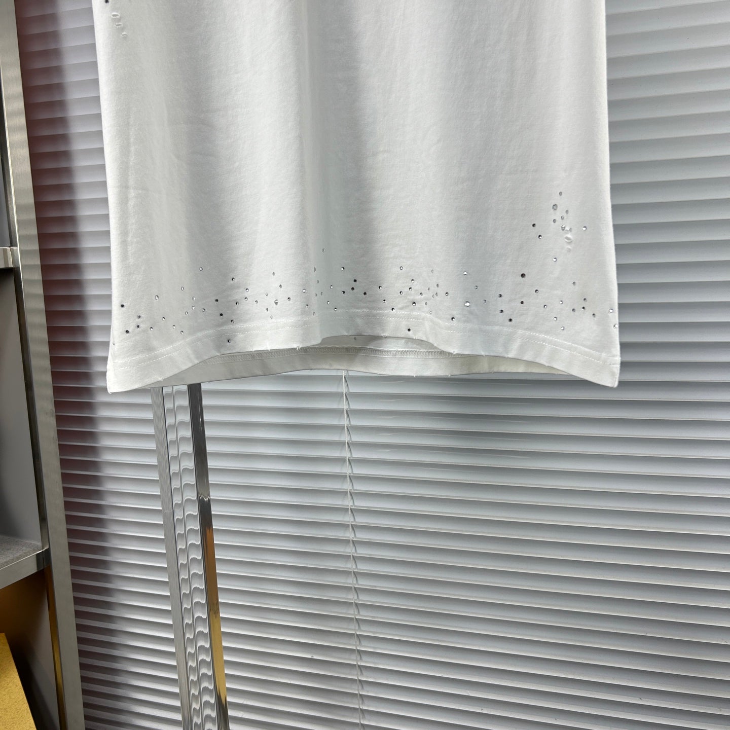 Versace white T-shirt hem with perforated stud detailing across the bottom