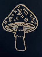 Embroidered gold and navy mushroom emblem on black T-shirt front