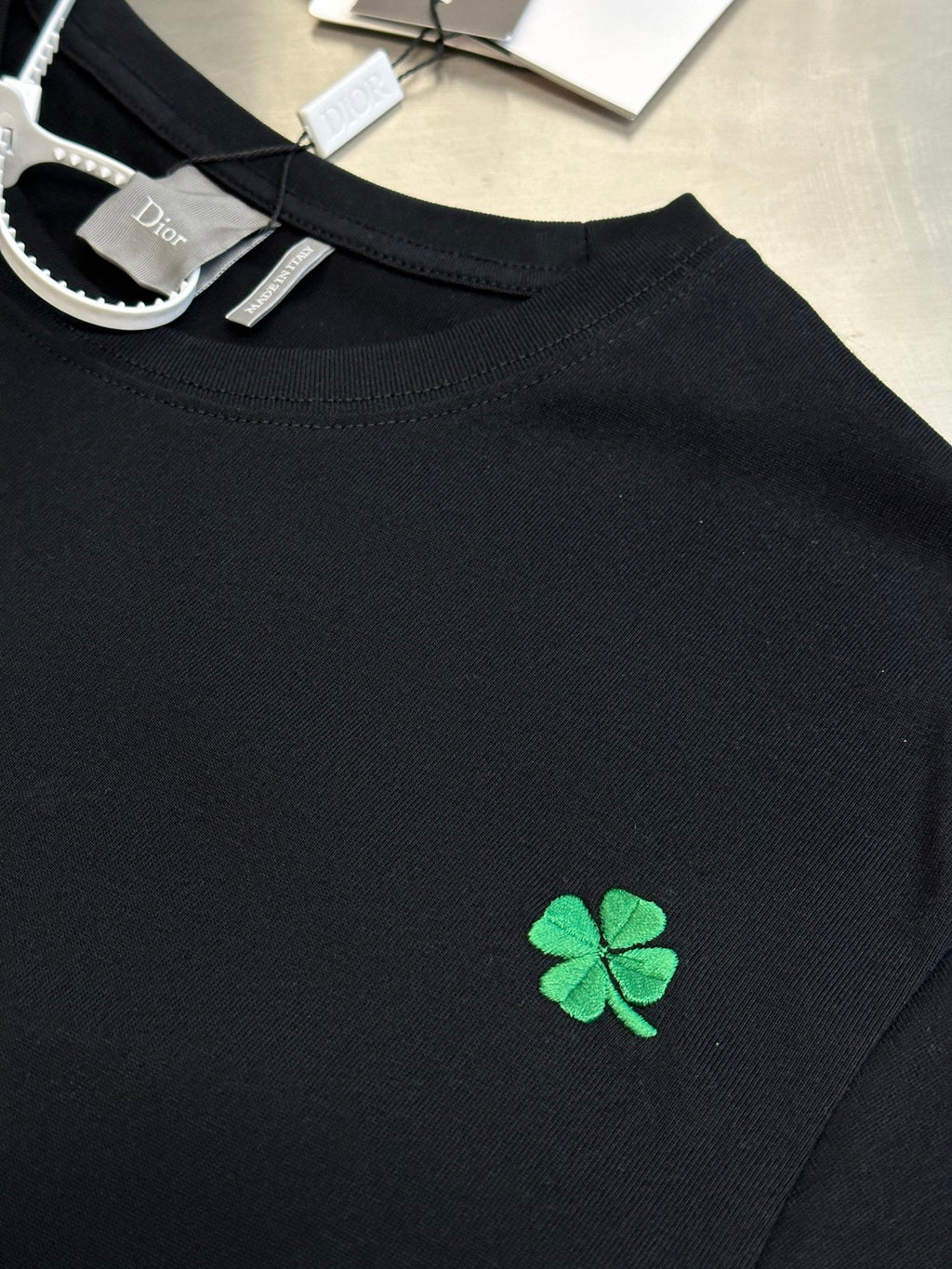 Black short-sleeve T-shirt with small green clover embroidery on chest