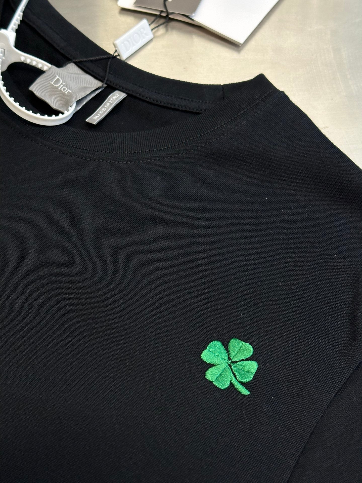 Dior dark T-shirt neckline with green clover patch and stitched collar edge