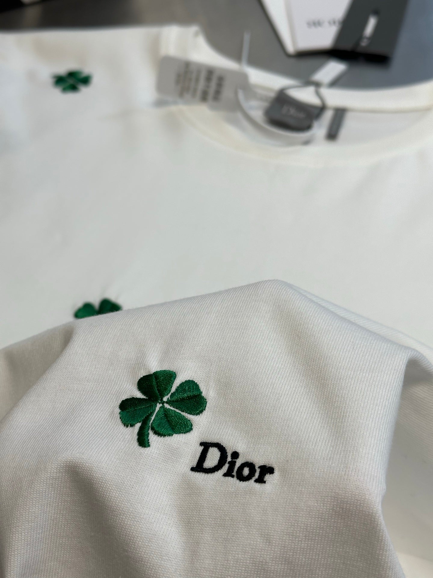White T-shirt with green clover and 'Dior' logo near center chest