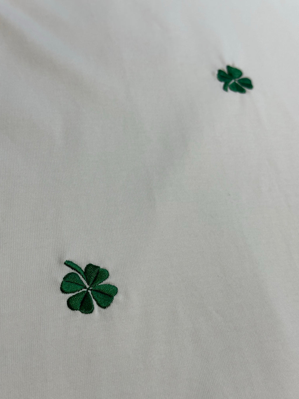 White fabric with green four-leaf clover embroidery