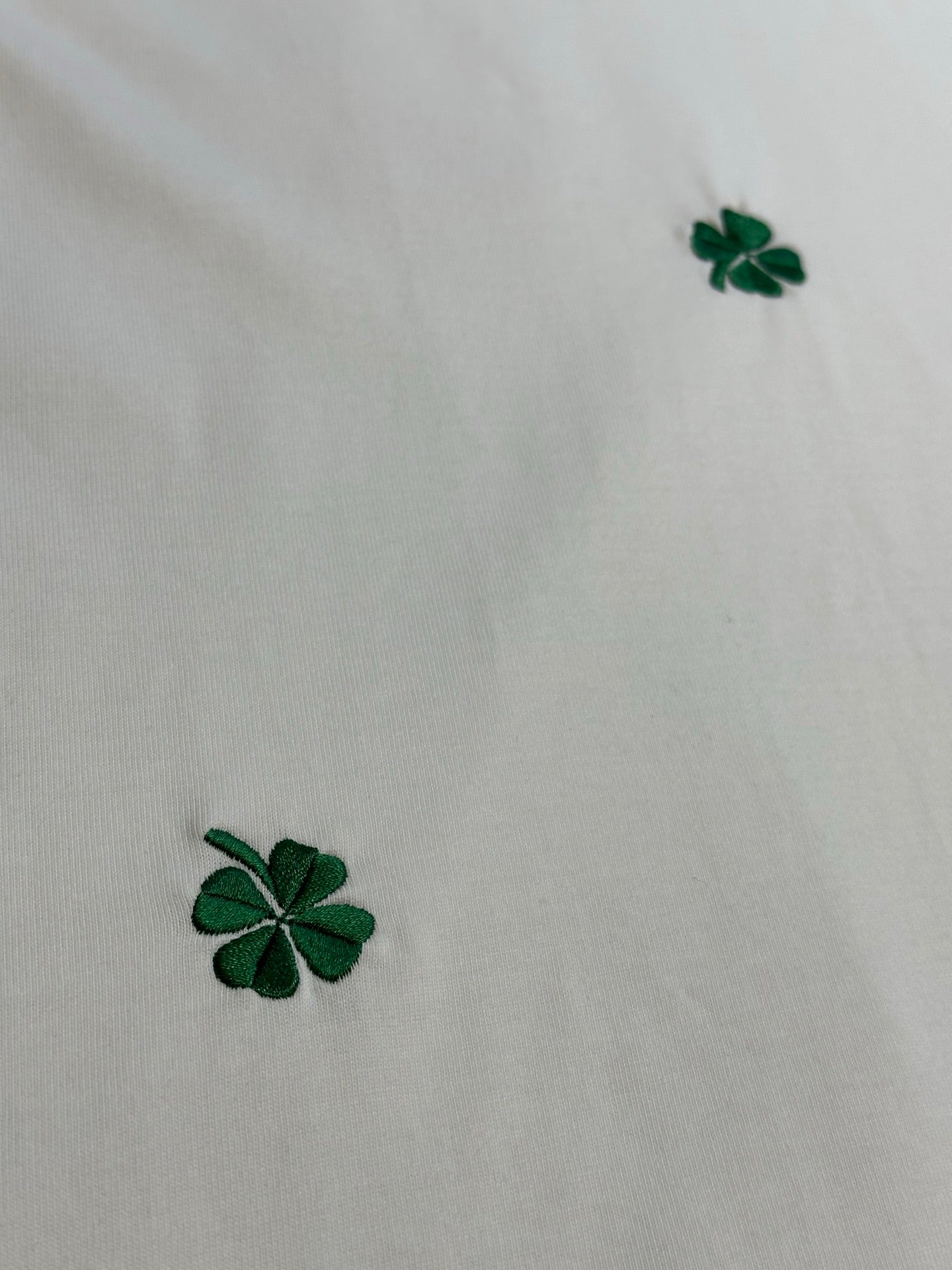 White T-shirt fabric with green four-leaf clover embroidery