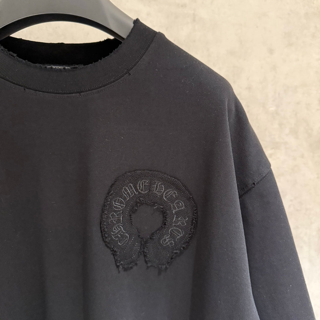 Black T-shirt with round chest emblem and short sleeves detail