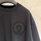 Black T-shirt with round chest emblem and short sleeves detail